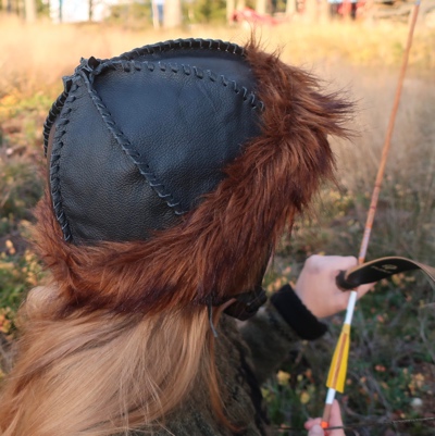 Kuvassa musta nahkainen kypäränpäällinen, jossa on ruskea karvareunus.